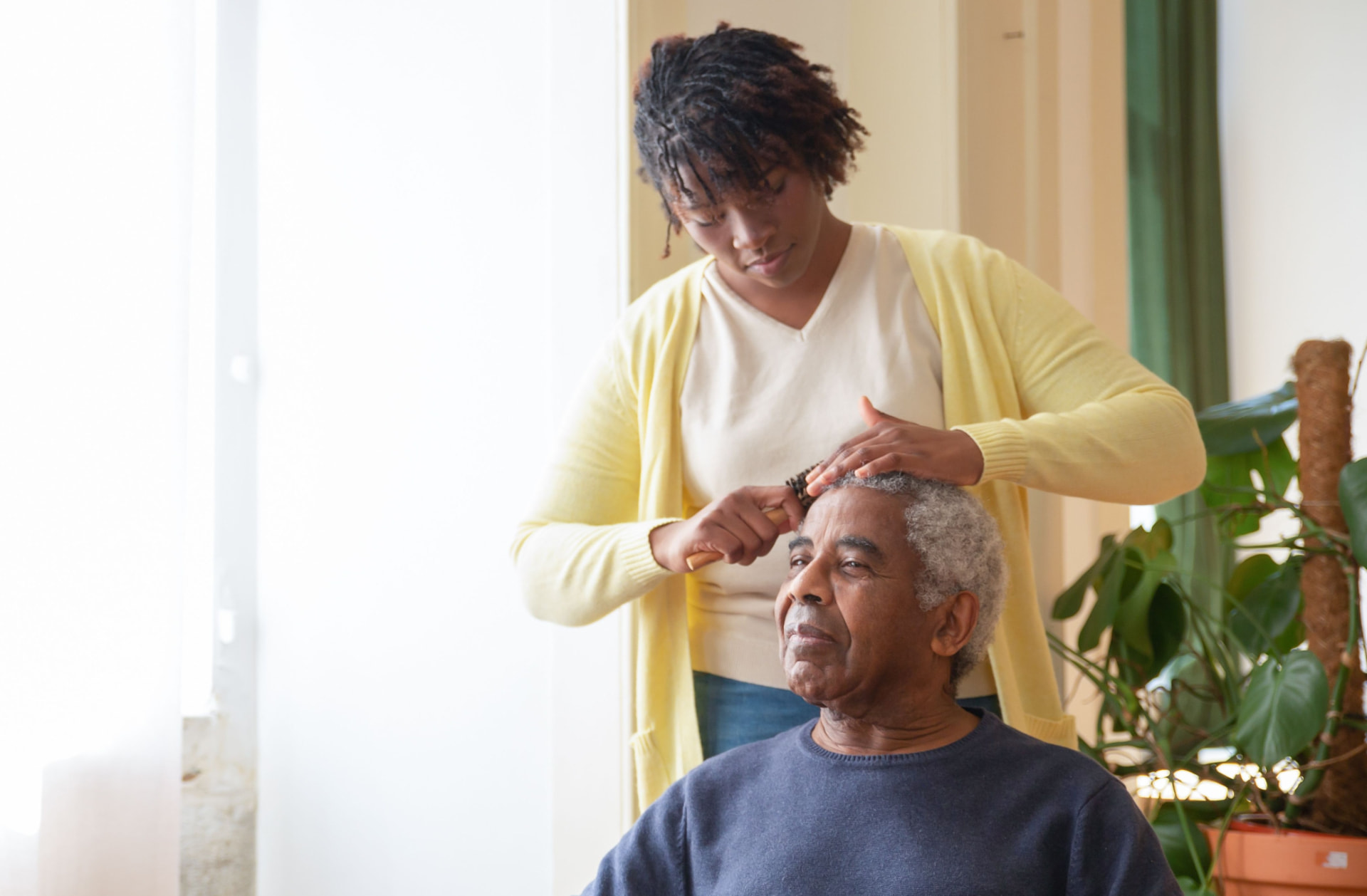 A caregiver helping an older woman with grooming at home